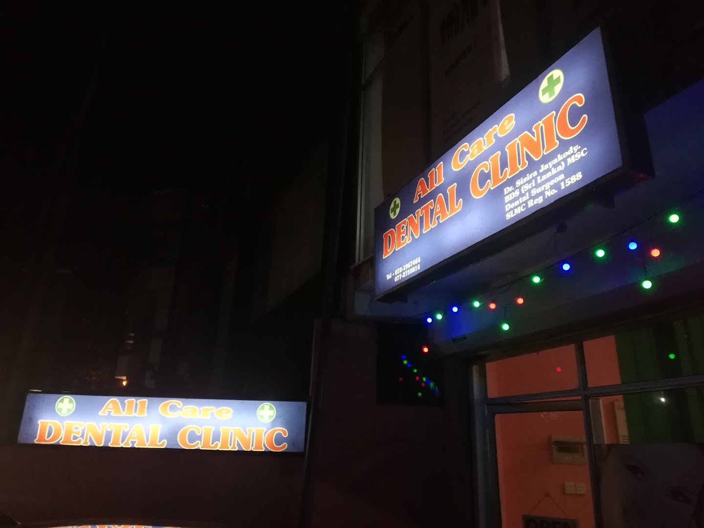 Illuminated All Care Dental signs outside the clinic in the evening